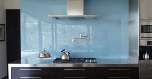 a dark stained kitchen with stainless steel appliances, a glossy blue glass backsplash for a more modern feel