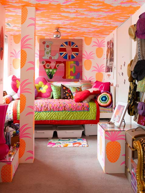 a super colorful and whimsical girl's room with a bold orange ceiling, a bold printed artwork, a bed with colorful printed bedding and curtains