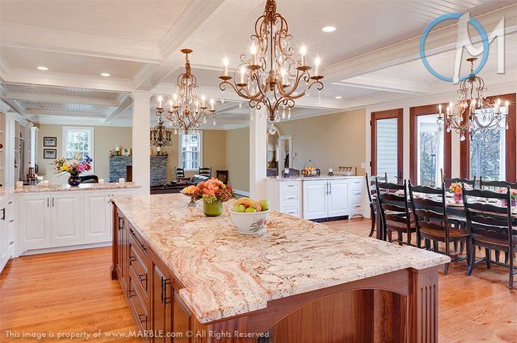 White cabinets with light colored stone countertops and a rich stained kitchen island with a grey stone countertop