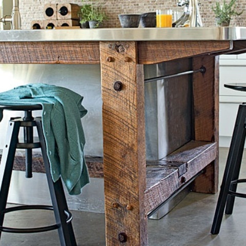 an industrial kitchen island of rough wood and a metal tabletop features soem storage space inside