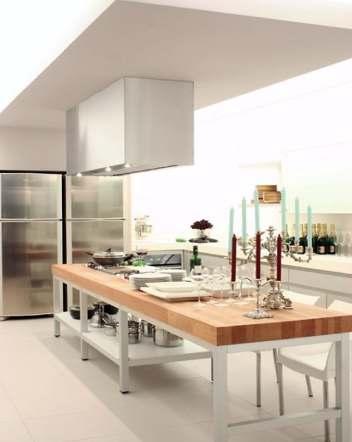 an oversized contemporary kitchen island with a metal base and a butcherblock countertop can be used for cooking and eating there