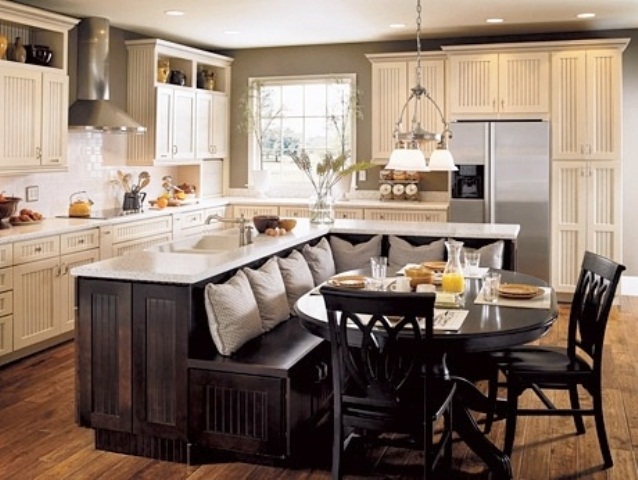 An oversized dark stained L shaped kitchen island with a built in bench and white countertops will save much space and give you everything you need