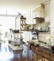 a vintage white kitchen island with carved out legs and a dark countertop looks very lightweight and elegant