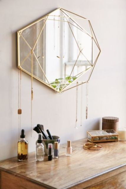 a bold and catchy geometrically shaped mirror in a gold frame, with some hanging crystals will be a nice idea for a boho space