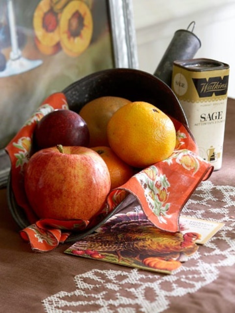 a vintage metal shovel with faux pumpkins and fruits and a bright napkin is a nice vintage decoration for Thanksgiving