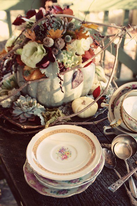 a vintage rustic Thanksgiving tablescape done with a farmhouse centerpiece - a pumpkin with blooms, leaves and berries and vintage porcelain and cutlery