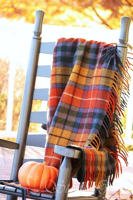 a grey chair with a bright plaid blanket and a pumpkin is a lovely idea for a cozy Thanksgiving party, especially outdoors