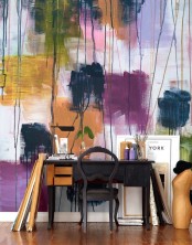 a jaw-dropping art studio with a fantastic bright watercolor accent wall, a black desk and a chair, a table lamp and some decor is a fun and cool idea
