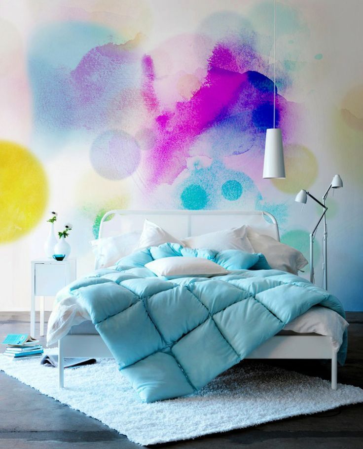 A bright watercolor accent wall behind the headboard, with a white bed, with turquoise bedding, a small white nightstand and a white floor lamp is a catchy and cool idea