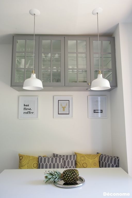 a contemporary grey, white and yellow breakfast nook with white IKEA Ranarp pendant lamps over the space is a chic and cool idea