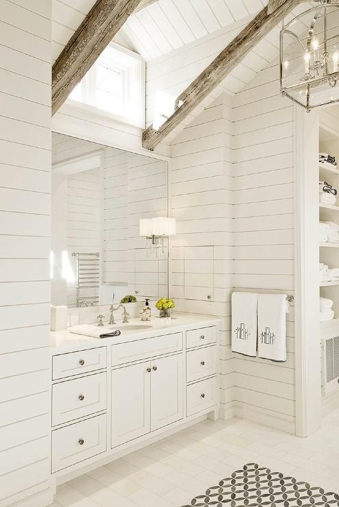 a neutral bathroom with wooden walls, wooden beams and a large vanity with a mirror