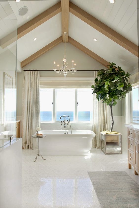 A seaside bathroom in neutrals, with wooden beams, built in lights, a tub, a shower space and windows for a view