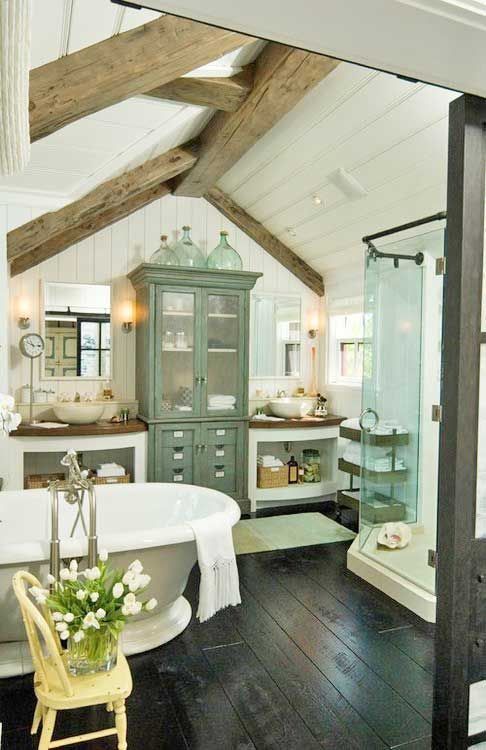 a farmhouse bathroom with a dark floor, wooden beams, a vintage tub and vintage furniture plus a shower space