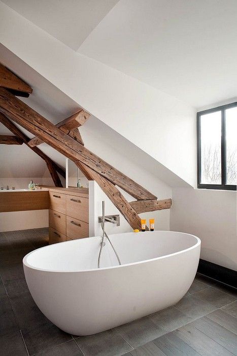 A modern farmhouse bathroom with white walls, wooden beams, a vanity and a free standing tub by the window