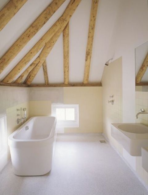 A neutral bathroom with a tile floor, warm colored walls, wooden beams and a free standing tub