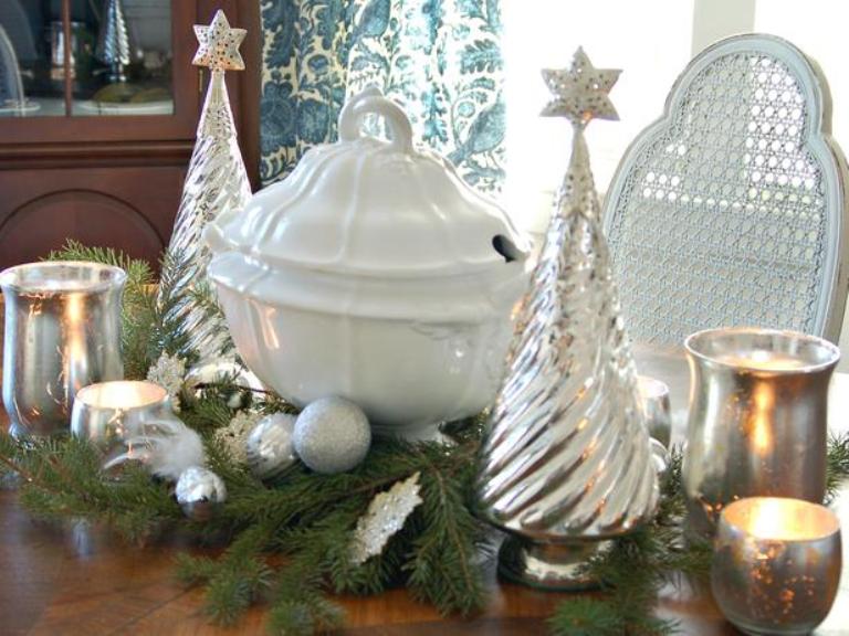 A silver Christmas centerpiece of mercury glass trees, mercury glass candleholders and silver ornaments plus evergreens is a stylish and shiny idea