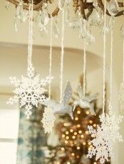 white snowflakes and silver glitter birds hanging from the chandelier are great and easy decoration for Christmas