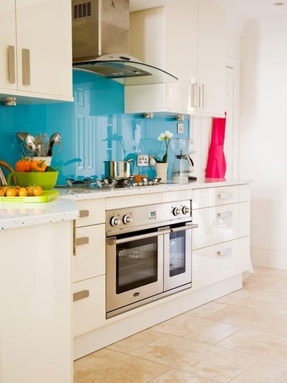 a white kitchen with a glossy blue backsplash and stainless steel appliances is a stylish space with a bold touch