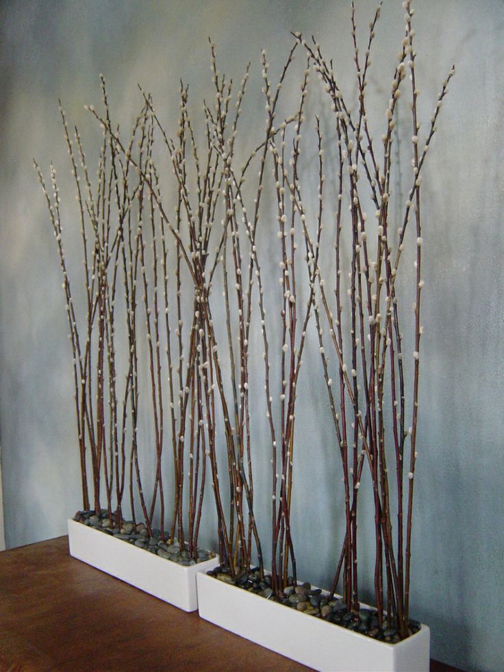 White planters with pebbles and tall willow are a cool decoration for spring   indoor or outdoor