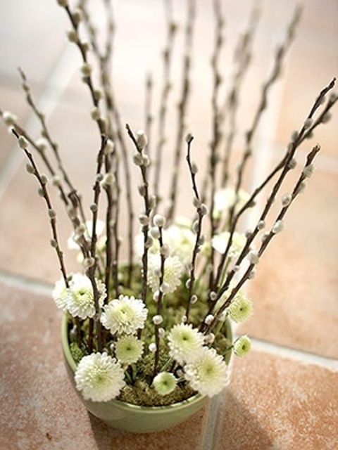 a grene planter with moss, neutral blooms and willow is a cool spring centerpiece or decoration