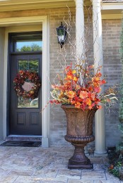 a vintage urn with bright faux leaves and blooms plus some branches is a timeless outdoor fall decoration