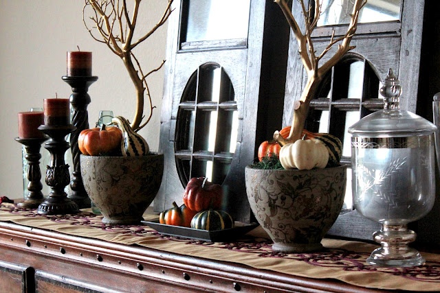 Patterned porcelain bowls with moss, faux veggies and branches plus faux pumpkins and bold candles for mantel decor