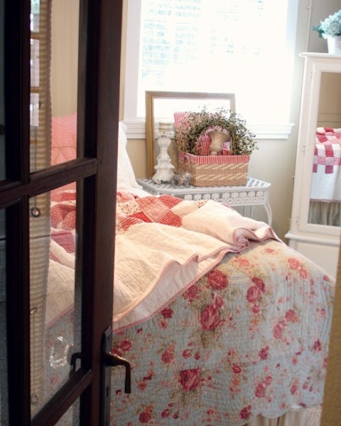 a shabby chic spring bedroom with bright floral and botanical print bedding, a greenery wreath and a bold basket