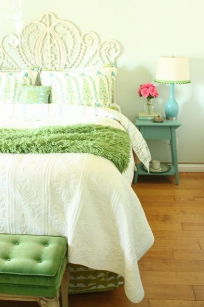 a colorful spring bedroom with botanical prints, a green blanket and a blue lamp