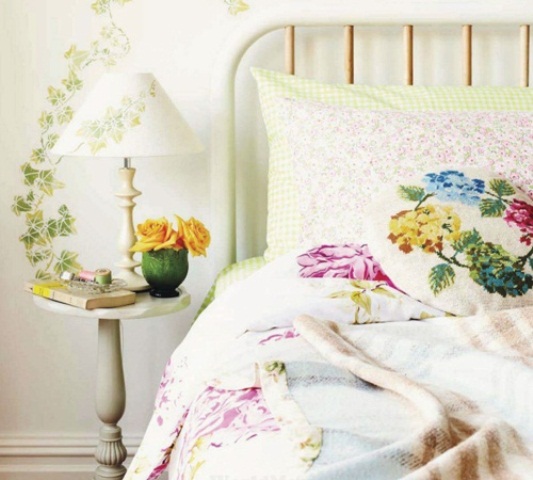 bright floral bedding and botanical print wallpaper and a lamp make the bedroom feel bright and inspired
