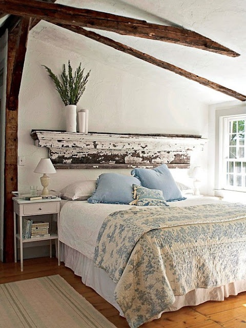 a shabby chic bedroom with blue and white bedding and greenery in a vase that make it spring-fresh