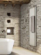 a bathroom fully clad with stone and with wooden beams on the ceiling plus a modern white tub