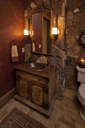 a cabin bathroom fully clad with stone, with a stained vanity with an aged metal sink looks very catchy and feels cozy