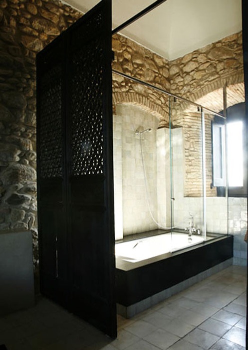 a modern bathroom with stone clad walls, a modern black shower space with a black space divider