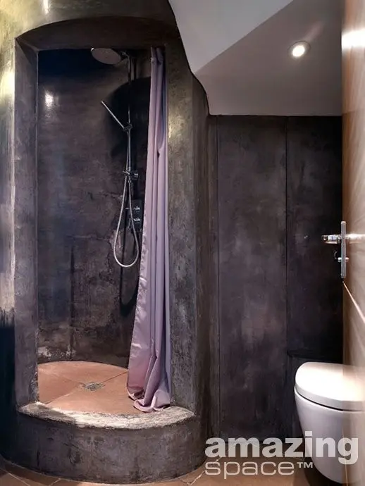 A wabi sabi bathroom with stone walls and a shower space plus tiles all over for a contrasting look