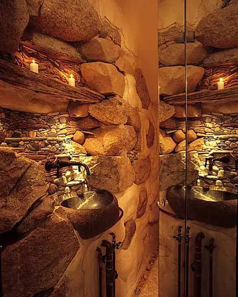 A wabi sabi bathroom with stone walls, a stone sink and built in lights for accenting