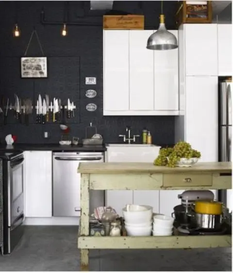 a kitchen with black walls and sleek white cabinets, black countertops, stainless steel appliances and a green dining table that is a kitchen island