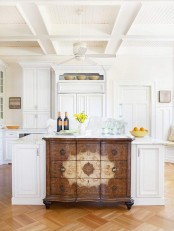 a white farmhouse kitchen with shaker style cabinets and a unique kitchen island – a large matching one with a refined vintage sideboard integrated is amazing