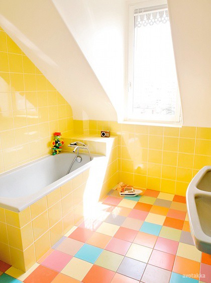 an attic bathroom clad with sunny yellow tiles and super colorful tiles on the floor and a skylight to fill the space with natural light